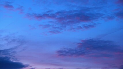 Wall Mural - A sunset timelapse showing a sky painted in soft pink and lavender hues, with scattered clouds gently drifting. The calm and dreamy colors create a serene atmosphere as daylight fades. Time lapse.
