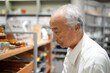 © Masakazu Tokashiki - In a stylish Japanese boutique filled with home goods, a Japanese man in his late 70s, wearing a white shirt, browses items with a relaxed expression, appreciating the carefully arranged displays.
