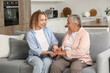© Pixel-Shot - Senior woman with her granddaughter holding hands on sofa at home