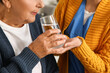 © Pixel-Shot - Senior woman drinking water with caregiver in kitchen, closeup