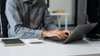 © Phushutter - A smart Caucasian businessman sits confidently at desk in modern indoor office, using laptop for online consulting, showcasing professionalism, success, digital expertise in corporate environment.