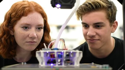 Poster - Two Students Look at 3D Printer with Clear Plastic Components in Laboratory Setting Innovation and Engineering