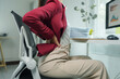 © crizzystudio - Businesswoman suffering from back pain while working on computer at office desk