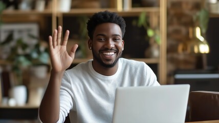 Poster - Smiling person waves hello while working on a laptop in a cozy indoor workspace