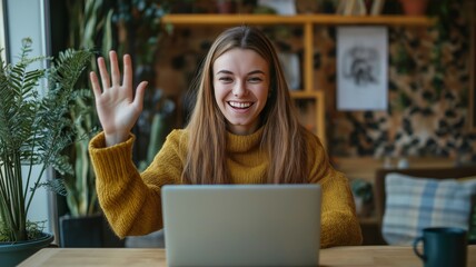 Poster - Young woman waves hello while using a laptop in a cozy, plant-filled workspace