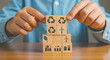© synthetic - Person stacking wooden blocks with ecology and sustainability symbols on a wooden surface table top