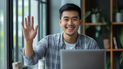 Poster - Young man waves hello while working on laptop in a modern workspace with greenery
