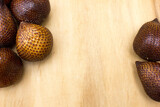 Some salak or snake fruits on a wooden board, background and textured, copy space.