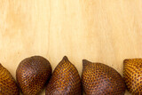 Some salak or snake fruits on a wooden board, background and textured, copy space.