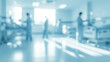 © al-sultan - Blurred hospital room with medical staff and beds in a bright environment.