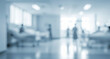 © al-sultan - Blurred hospital ward interior with beds and figures in the background.