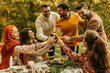 © La Famiglia - Friends toasting wine glasses celebrating thanksgiving dinner outdoors in forest