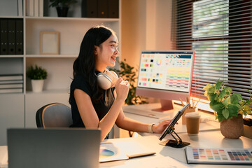 female graphic designer using digital tablet in a modern workspace filled with color charts and desi