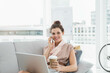 © WavebreakMediaMicro - Woman sitting on sofa in office lounge holding coffee cup, multitasking on smartphone and laptop