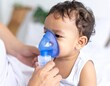 © SSuperTier - Close-up image of a small hand gently holding a blue nebulizer, emphasizing the delicate interaction between the device and the user, likely a child. The nebulizer's transparent mask and blue chamber