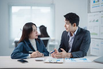 Aufkleber - Two asian business partners are discussing financial charts and graphs while sitting at office desk, analyzing company performance and planning investment strategy