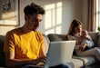 © starush - Young man working on a laptop while a woman holds a baby in a cozy living room
