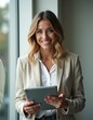 © Evgeny - Smiling businesswoman using tablet near window in office