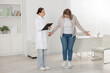 © New Africa - Weight loss. Overweight woman standing on scales during consultation with nutritionist in clinic