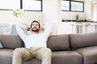 © Wavebreak Media - Man relaxing on gray sofa in open-plan living area near dining table with white flowers