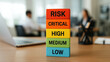 © AiDesign - Colorful wooden blocks with risk levels critical high medium and low placed on wooden table in office background showing business assessment and planning concept