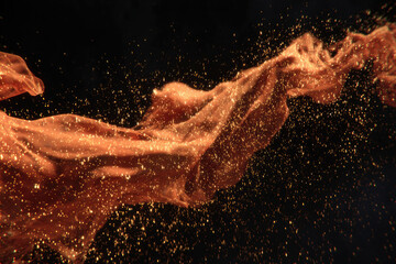 Aufkleber - Orange fabric floats gracefully with sparkling particles drifting in air, creating dreamy, ethereal atmosphere against dark background