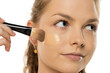 © vladimirfloyd - Close-up of young woman applying liquid foundation with makeup brush on cheek, showing smooth application process against white background