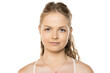 © vladimirfloyd - Portrait of young woman with blue eyes and wavy hair in ponytail, wearing white top and delicate necklace against clean white background