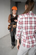 © Andrii Lysenko - Female foreman builder in hardhat holding renovation plan standing talking with woman homeowner in empty apartment