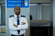 © Wavebreak Media - African American security officer standing with arms crossed at airport checkpoint showing badge