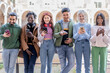 © Lomb - Diverse group of young adults standing in a row using smartphones in urban setting with joyful expression