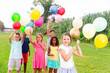 © JackF - Joyful barefoot kids having fun together while playing with balloons on field.