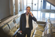 © Wavebreak Media - Businessman standing in terminal bench seating holding smartphone to ear and carrying briefcase