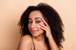 © deagreez - Portrait of a young woman with curly hair posing against a beige background, showcasing beauty and confidence in casual attire