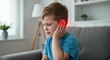 © Pics_With_Love - Young caucasian child boy experiencing ear pain sitting on couch at home, hand on ear with red glow indicating discomfort, indoor pediatric health concept
