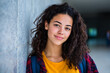 © PrettyStock - Portrait Of A Smiling Young Woman With Curly Hair Leaning Against A Wall Outdoors