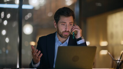 Poster - Hardworking manager talking mobile phone looking laptop at dark office closeup.