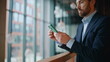 © stockbusters - Serious manager reading cellphone message standing at office lobby closeup.