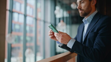 Poster - Serious manager reading cellphone message standing at office lobby closeup. 