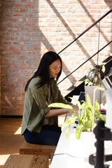 Asian woman coding on laptop at modern office desk, focused and productive