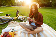 © Home-stock - Young lady using laptop at summer garden park and eating fruit salad, enjoy relaxing outdoors having picnic on sunny day