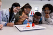 © Wavebreak Media - Diverse students in science class experimenting with beaker, wearing safety goggles, at school