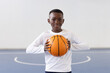 © Wavebreak Media - Smiling african american boy holding basketball on indoor court, ready for practice