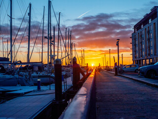 Wall Mural - A sun rise over a marina with silhouettes of masts of many boats and yachts docked. Teal and orange color scheme. Calm and relaxing mood. Port of Galway, Ireland.