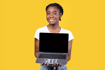 Aufkleber - Cheerful Black Lady Showing Laptop Blank Screen Holding Computer Standing Posing On Yellow Studio Background, Smiling To Camera. African Woman Recommending Website. Mockup