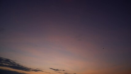 Wall Mural - a sunrise timelapse capturing the sky’s soft transition from deep purple to warm pinks and oranges, 