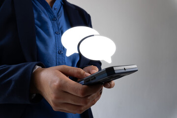 Poster - A business person  holding a smartphone with two speech bubbles on the screen, representing an online chat concept.