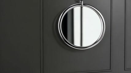 Poster - Round silver frame suspended on a chain against a dark gray paneled wall, providing a clean and modern display space.