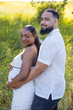 © Bogdan Pictures - On a beautiful, sunny summer day, a loving African American couple enjoys an intimate and affectionate moment outdoors, joyfully celebrating their exciting pregnancy in a stunning natural setting