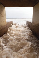 Aufkleber - Vintage-Inspired Coastal Flood Drainage Culvert with Rushing Water Flowing toward Ocean Inlet for Storm Management and Infrastructure Resilience
